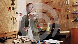 Portrait of woman in carpenter workshop showing wooden toys