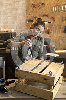 Portrait of woman in carpenter workshop working with screwdriver