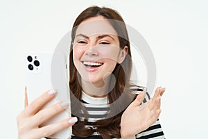 Portrait of woman chats on mobile phone video app, talks at smartphone camera, laughing and looking at telephone