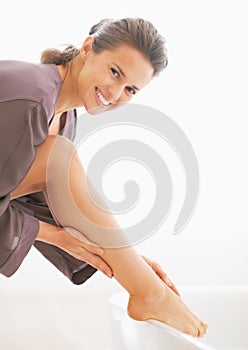 Portrait of woman checking leg skin softness in bathroom