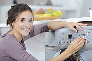 portrait woman choosing programme on washing machine photo