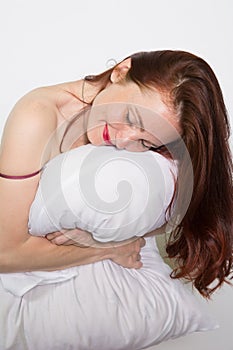 Portrait of a woman with closed eyes resting on a pillow over white background