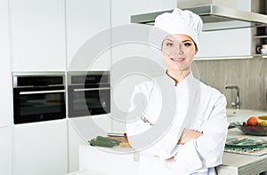 Portrait of woman cook who is standing on her work place in the kitchen