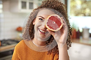 Woman covering her eye with grapefruit