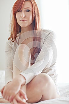 Portrait, woman and cozy on mattress for relax with morning, casual weekend and natural light in home. Ginger girl, rest