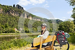 Portrait of woman cyclist resting on a bench in nature.