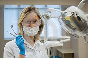 Portrait of woman dentist with tools over medical office background.