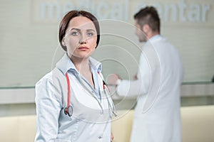 Portrait of woman doctor at hospital corridor, looking at camera.