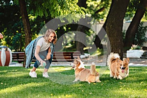 Portrait of woman with dogs Welsh Corgi Pembroke in dog park