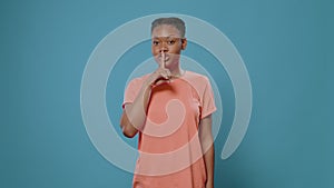 Portrait of woman doing shush gesture with finger on mouth