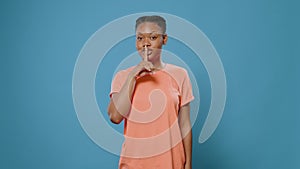 Portrait of woman doing shush gesture with finger on mouth