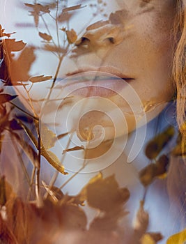 Portrait of a woman with a double exposure, the girl and the blurred nature of the photo is not in focus. The leaves on the woman.