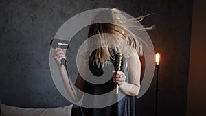 Portrait of a woman dries the hair dryer and sing into your hairbrush