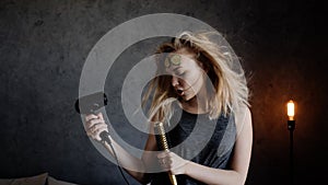 Portrait of a woman dries the hair dryer and sing into your hairbrush