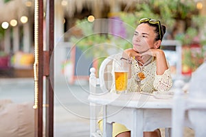 Portrait of woman drinking beer at beach cafe