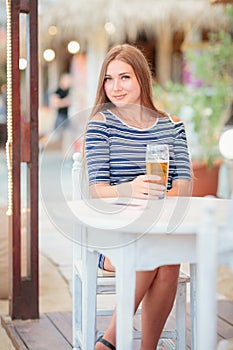 Portrait of woman drinking beer at beach cafe