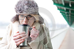 Portrait of woman drinking coffee from insulated drink container during winter