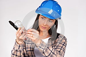 Portrait of a woman electrician in a hard hatwith a light bulb and wire cutters on white background