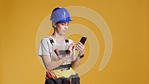 Portrait of woman engineer using smartphone to browse internet