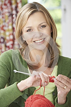 Portrait Of Woman Enjoying Knitting Garment At Home photo