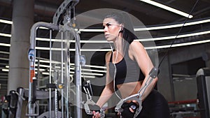 Portrait of woman exercising power cable crossover for chest muscles at gym