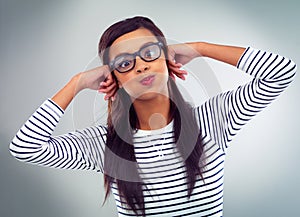 Portrait, woman and expression in studio, funny and hands on gray background. Humor, comedy and eyewear for happy female