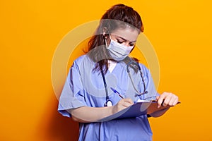 Portrait of woman with face mask and taking notes
