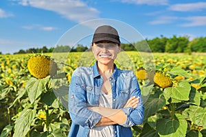 Portrait of woman farmer, agronomist in field with ripe sunflower