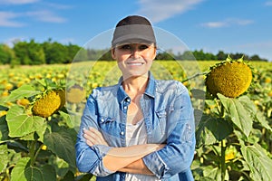 Portrait of woman farmer, agronomist in field with ripe sunflower