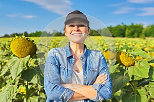 Portrait of woman farmer, agronomist in field with ripe sunflower