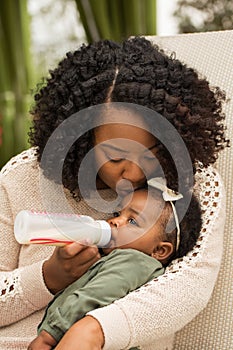 Portrait of woman feeding her daughter with a bottle.