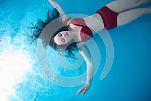 Portrait of woman floating in swimming pool. Relaxation and spa therapy. Copy Space.