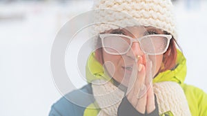 Portrait of a woman in glasses covered with hoarfrost. The girl is freezing and forgot gloves in very cold weather and