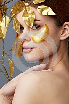 portrait woman golden leaves luxury skin care face patches bare shoulders isolated background