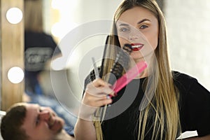 Portrait of woman hairdresser holding combs and scissors