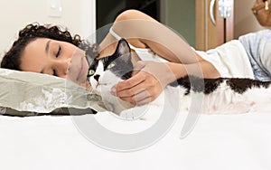 Portrait of woman hand petting black and white cat. Room interior on background. Concept of love to