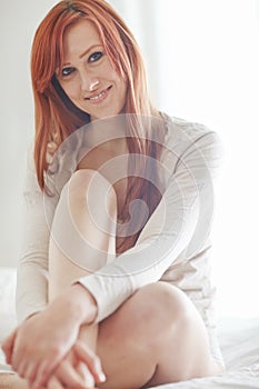 Portrait, woman and happy on mattress for relax with morning, casual weekend and natural light in home. Ginger model