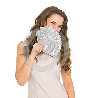 Portrait of woman hiding behind fan of dollars