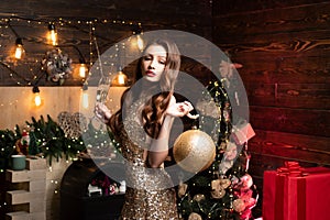 Portrait of woman holding big golden christmas bauble. Young woman with Christmas decoration. Santa girl celebrate