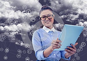 Portrait of woman holding digital tablet with connecting icons and cloud in background