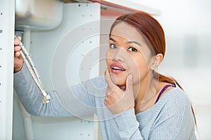 Portrait woman holding disconnected pipes under sink