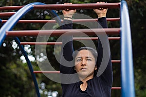 Portrait of a woman holding an exercise bar in a park