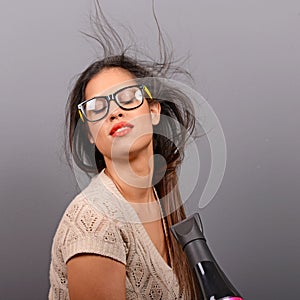 Portrait of a woman holding hair dryer against gray background