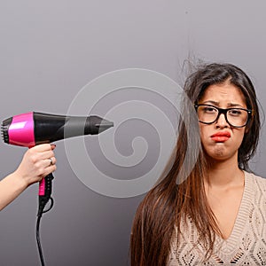 Portrait of a woman holding hair dryer against gray background