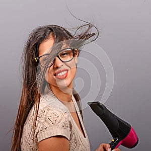 Portrait of a woman holding hair dryer against gray background