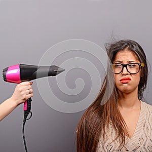 Portrait of a woman holding hair dryer against gray background