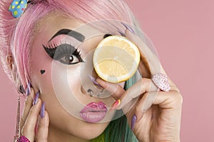 Portrait of a woman holding slice of lime in front of her eyes