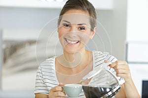 portrait woman at home pouring herself coffee