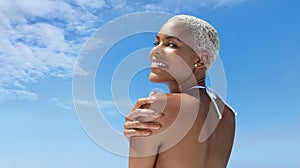 Portrait of a woman on the hot summer beach, enjoying a holiday by the sea. Seen from behind, with her hand on her shoulder,