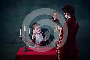 Portrait of woman in image of vampire looking in mirror to see her endless youth. Male looking at woman. Immortal family photo